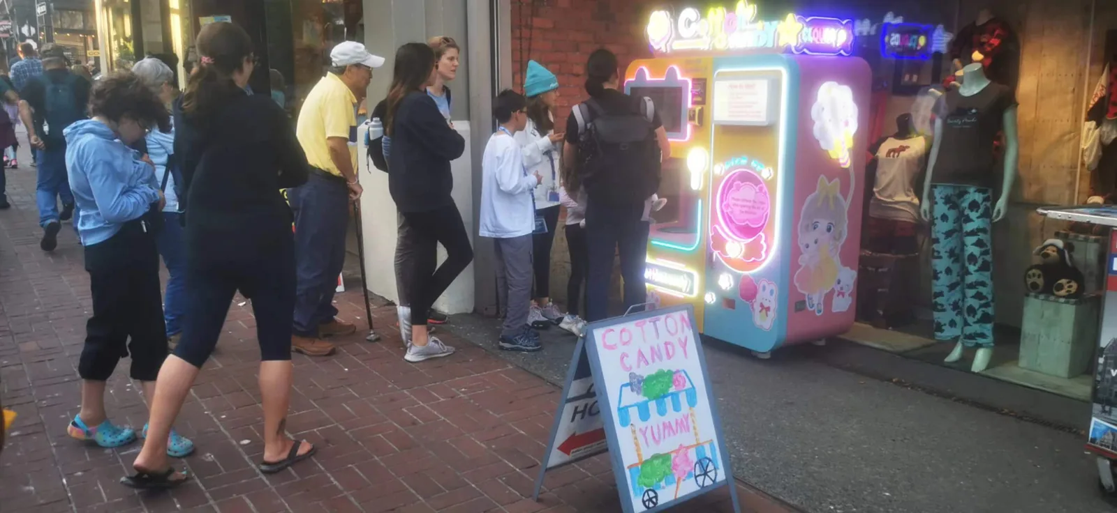 Customer holding a large cloud of cotton candy next to a vending machine close-up at night